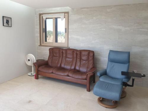 a living room with a leather couch and a blue chair at Sea and Noeul Healing House in Seogwipo