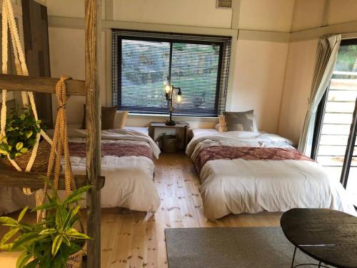 1 dormitorio con 2 camas y ventana en １日1組様限定　「ほしな屋」 en Nagano