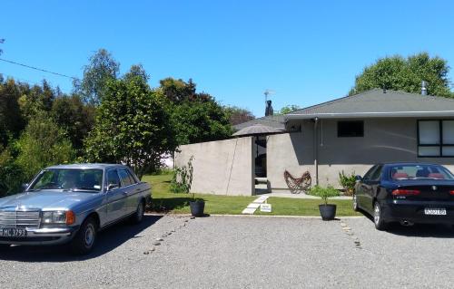 zwei Autos, die in einer Einfahrt vor einem Haus geparkt sind in der Unterkunft A little bit of country on the city's doorstep in Napier