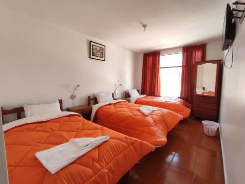 Duas camas num quarto com um edredão laranja em Sunrise Guest House em Huaraz