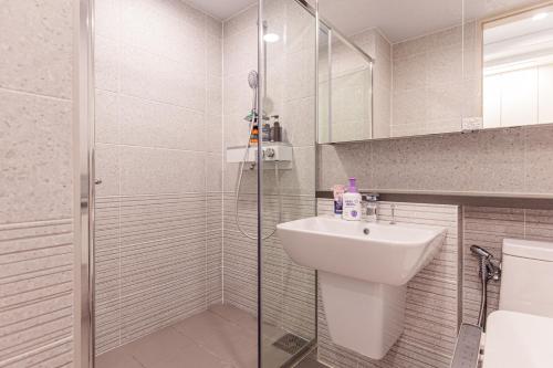 ein Bad mit einer Dusche, einem Waschbecken und einem WC in der Unterkunft Lotte Castle Marina in Yeosu