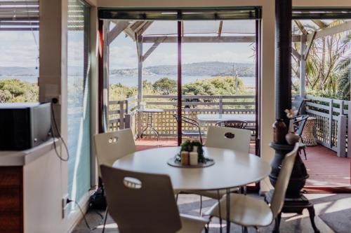 Una habitación con una mesa y sillas en un balcón. en Cool and Calm on Kiama, en St Helens