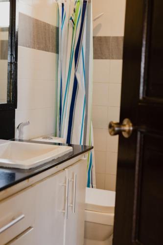 a bathroom with a sink and a shower curtain at Amami Beachfront Villa with Private Beach in Puerto Galera