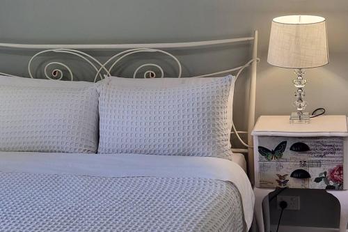 a bed with a white comforter and a table with a lamp at Heritage cottage in South Hobart in Hobart