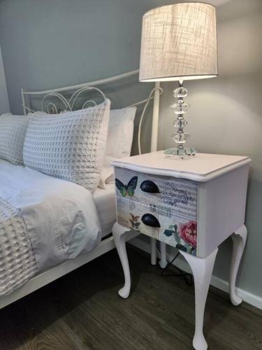 a nightstand with a lamp on it next to a bed at Heritage cottage in South Hobart in Hobart