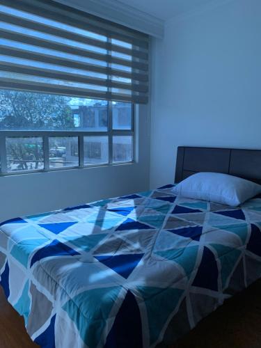 Schlafzimmer mit einem Bett und einem Fenster mit Jalousien in der Unterkunft Bogotá Kings 300 in Bogotá