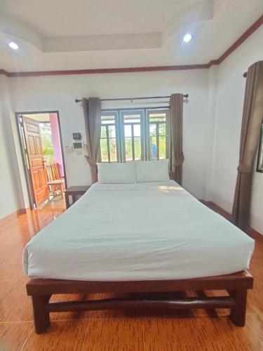 a large white bed in a room with windows at Chatchawan Resort in Ban Tha Sao