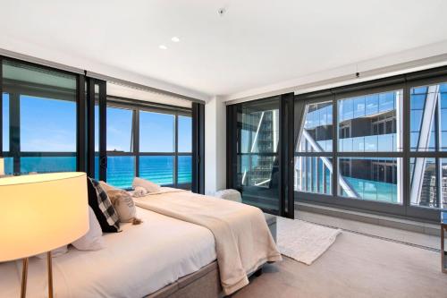 a bedroom with a bed and large windows at Jewel Broadbeach Luxury Apartment - CoastHM in Gold Coast