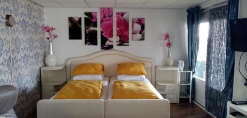 a bedroom with a white bed and some paintings on the wall at B&B aan het water in Earnewâld