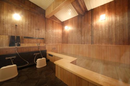 a bathroom with wooden walls and two toilets in it at Iroriyado Hidaya in Takayama
