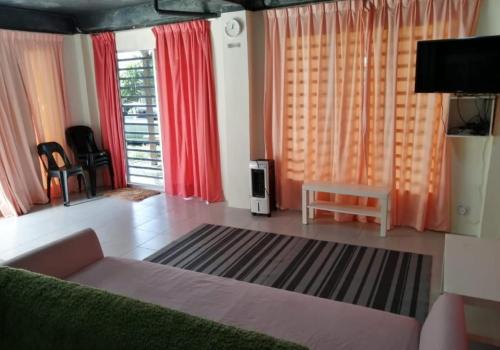 a living room with a couch and red curtains at CHALET MORIS D' RUMAH BONDA RIVER VIEW in Kampong Senawar