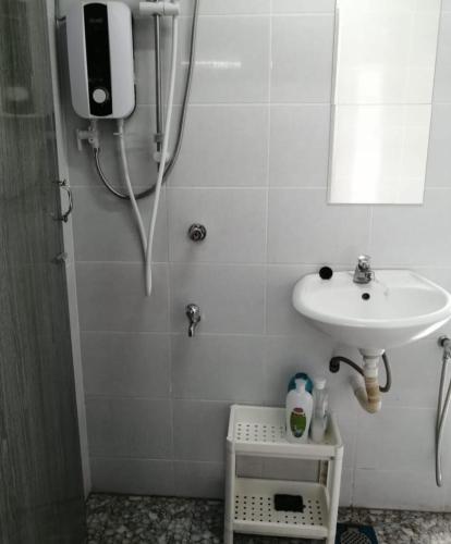 a white bathroom with a sink and a shower at CHALET MORIS D' RUMAH BONDA RIVER VIEW in Kampong Senawar