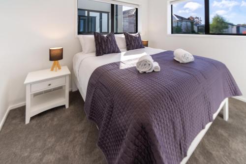 a bedroom with a bed with two towels on it at Central City Awaits 2 bed 2 bath with carpark in Christchurch