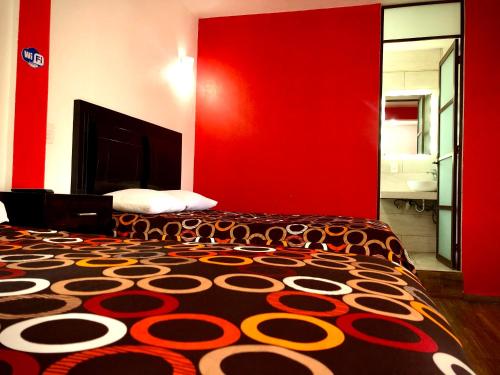 ein Schlafzimmer mit einem Bett mit einer roten Wand in der Unterkunft HOTEL LA GRAN MANZANA in Zacatlán