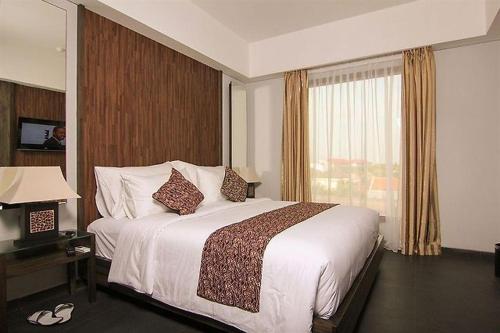 a hotel room with a large bed and a window at Ping Hotel Seminyak Bali in Seminyak