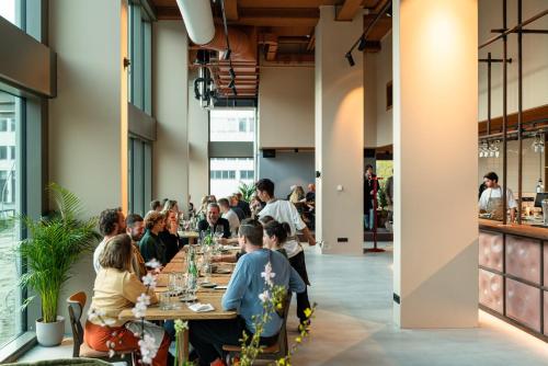 a group of people sitting at tables in a restaurant at Hotel Jansen Amsterdam Bajeskwartier in Amsterdam