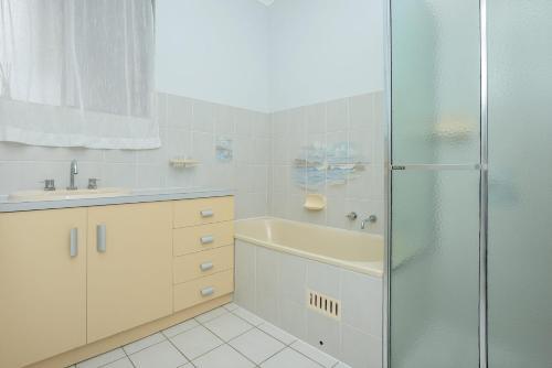 een badkamer met een douche, een wastafel en een bad bij Boomer - 4 Railway Tce, Port Elliot in Port Elliot