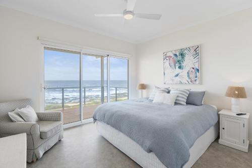 a bedroom with a bed and a large window with the ocean at Ray's Beach House at 58 Ocean Parade Middleton in Middleton