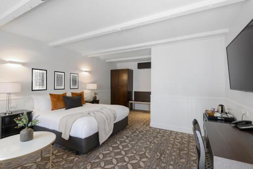 a hotel room with a bed and a flat screen tv at Scenic Hotel Cotswold in Christchurch