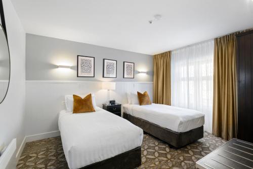 a hotel room with two beds and a window at Scenic Hotel Cotswold in Christchurch