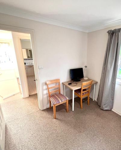 a room with a desk with a computer and two chairs at 3 Bedroom Town house near Gosford CBD Sleeps 6 plus in Gosford