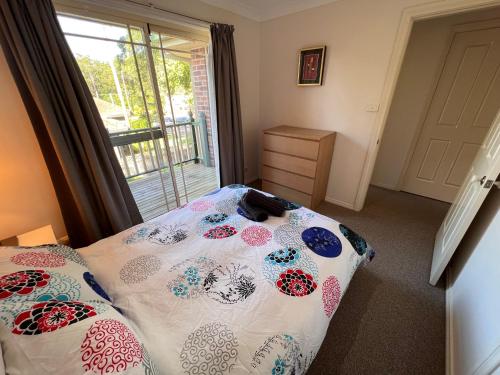 a bedroom with a bed with a comforter and a window at 3 Bedroom Town house near Gosford CBD Sleeps 6 plus in Gosford