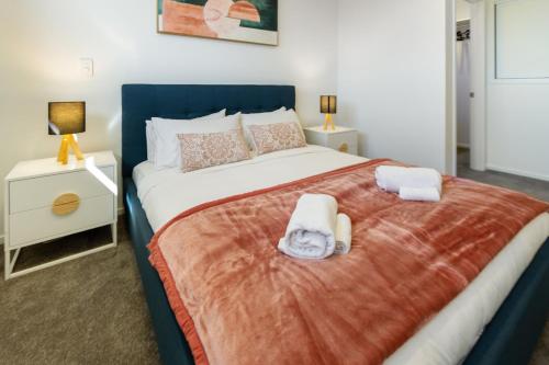 a bedroom with a large bed with two towels on it at The City's Best Kept Secret 2 bed 2 bath in Christchurch