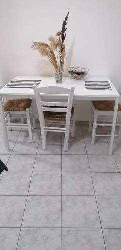 a white table and chairs with a plant on it at menidistudios in Menídion