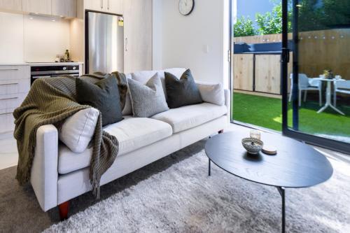 een woonkamer met een witte bank en een tafel bij The City's Best Kept Secret 2 bed 2 bath in Christchurch