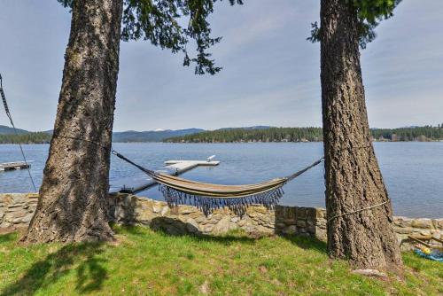 een hangmat tussen twee bomen naast een meer bij Huvila Haven Lake Front Home with Dock and Hot Tub 