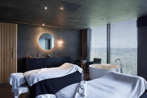 a bathroom with two beds and a tub and a sink at RACV Torquay Resort in Torquay