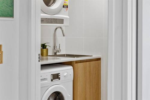 a kitchen with a washing machine and a sink at 1 Bedroom Central Mooloolaba Resort with Pool, Spa, Mini Golf in Mooloolaba