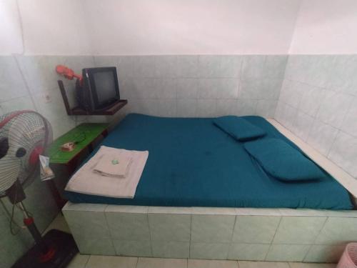 a small bedroom with a blue bed and a tv at Hotel O Tetirah Homestay in Salatiga