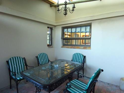 a glass table with four chairs and a window at De Kelder in Cape Town
