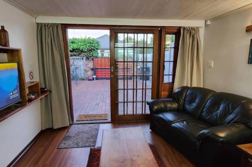 a living room with a leather couch and a sliding glass door at De Kelder in Cape Town