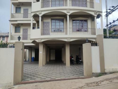 Un gran edificio blanco con dos motocicletas estacionadas frente a él. en Magvaris Comfort Inn, en Shillong