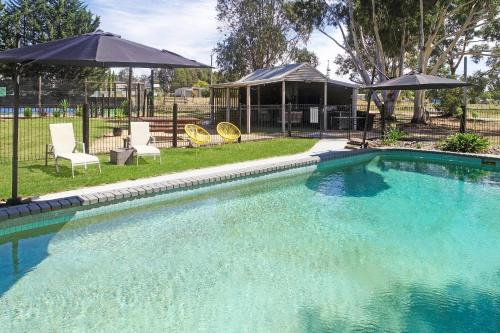 a swimming pool with two chairs and an umbrella at All Seasons Mansfield in Mansfield