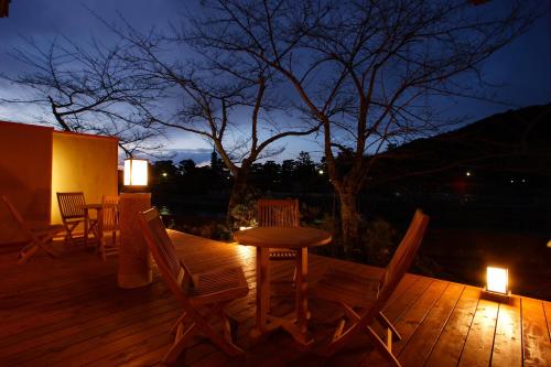 a wooden deck with a table and chairs at night at Hanayashiki Ukifune-en in Uji