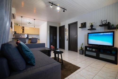 a living room with a couch and a flat screen tv at Oceanus Summer House in Salamina