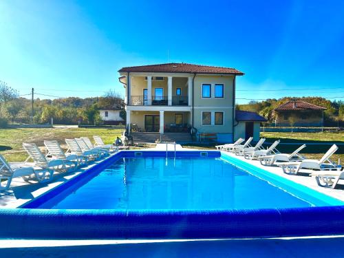 a swimming pool with chairs and a house at Guest House Gerasimovi in Elena