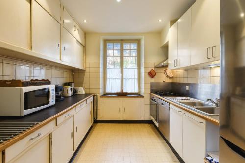 une cuisine avec des armoires blanches et une fenêtre dans l'établissement Grand Chalet des Moussoux - Happy Rentals, à Chamonix-Mont-Blanc