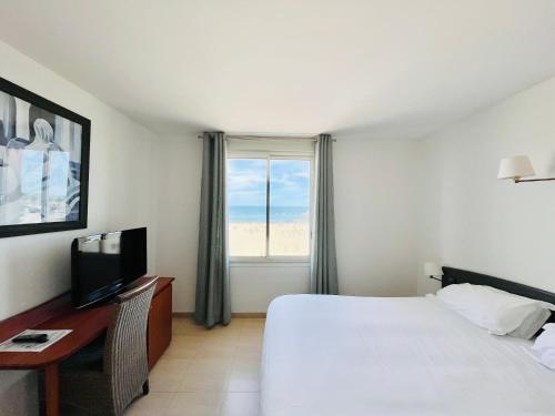 une chambre avec un lit et un bureau avec une télévision dans l'établissement Les Alizes, à Palavas-les-Flots