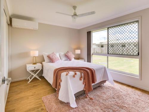 a bedroom with a bed and a large window at Breeze in Toogoom in Toogoom
