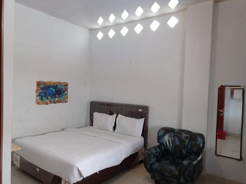 um quarto com uma cama e uma cadeira em DAMAI GUEST HOUSE LAUCIMBA KABANJAHE em Kabanjahe