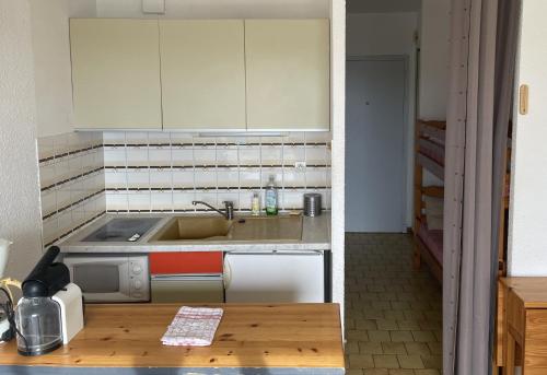 une petite cuisine avec un évier et une cuisinière dans l'établissement Vue ensoleillée sur le port de Gruissan, à Gruissan