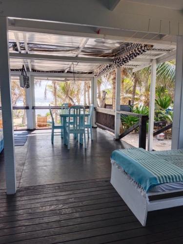 eine abgeschirmte Veranda mit einem Tisch und einem Bett auf einer Terrasse in der Unterkunft Poppies Beach Bach in Matavera