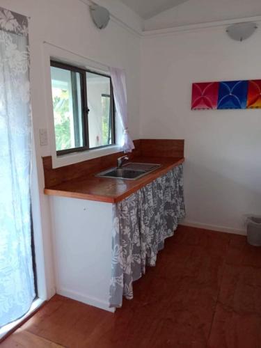 a kitchen with a sink and a window at Poppies Beach Bach in Matavera