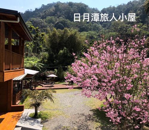 a bush with pink flowers in front of a building at Cabin of Sun Moon Lake in Yuchi