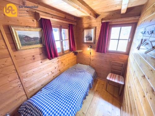 ヴェルコランにあるChalet Vercoquinの木造キャビン内のベッド1台が備わる小さな客室です。
