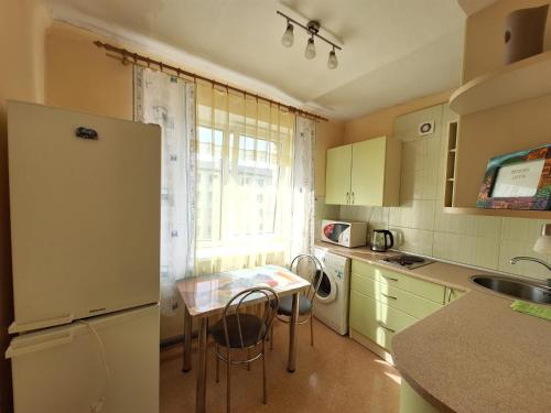 a small kitchen with a table and a refrigerator at Kandavas 2 in Daugavpils